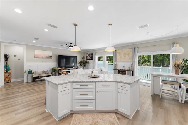 633 W Pope Rd, Saint Augustine, FL 32080 - kitchen featuring crown molding, a center island, open floor plan, white cabinets, and light stone counters