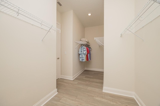 walk in closet with light hardwood / wood-style floors