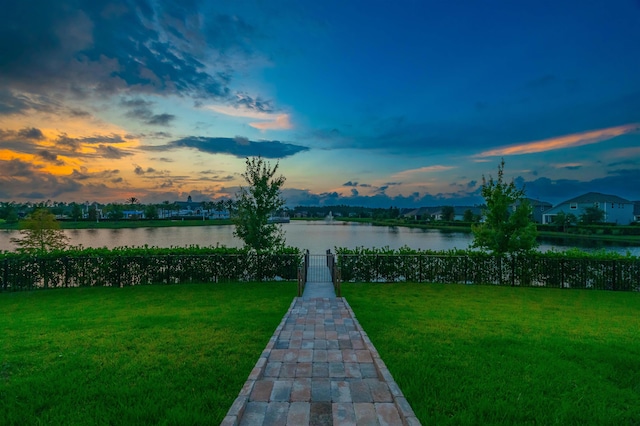 yard at dusk featuring a water view