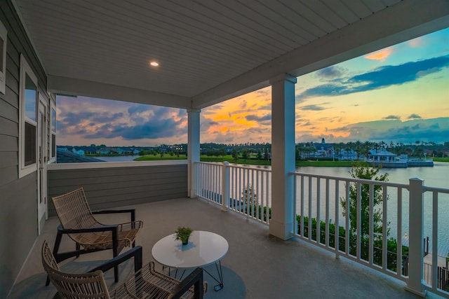 balcony at dusk featuring a water view