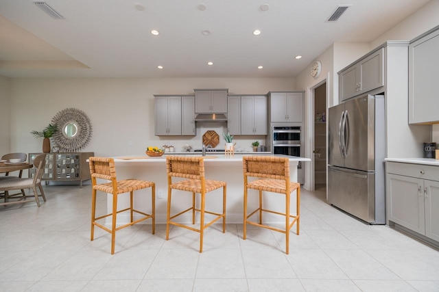 kitchen featuring a breakfast bar, appliances with stainless steel finishes, and gray cabinets