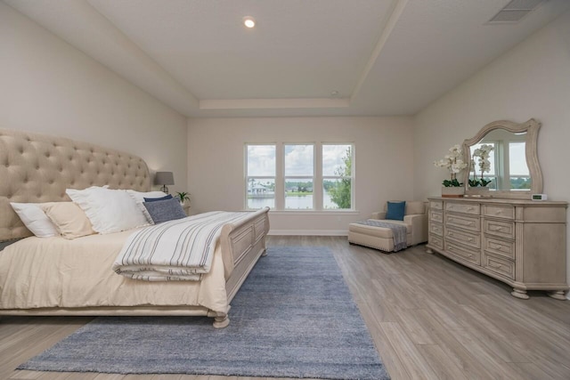 bedroom featuring a raised ceiling and light hardwood / wood-style flooring