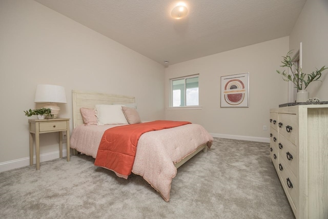 bedroom featuring a textured ceiling, light carpet, and vaulted ceiling