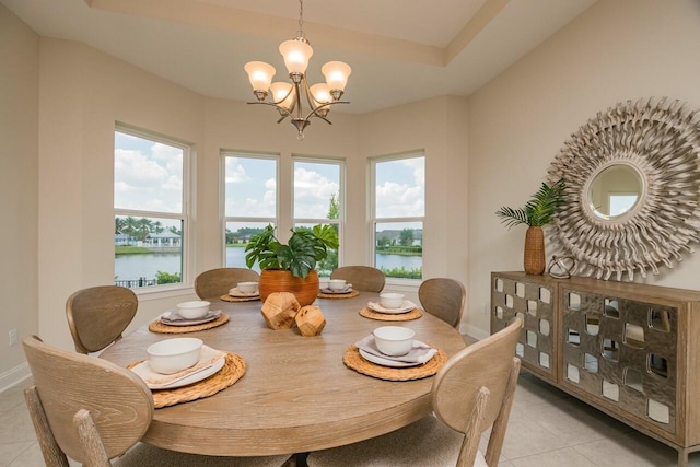 tiled dining space featuring a water view and a chandelier