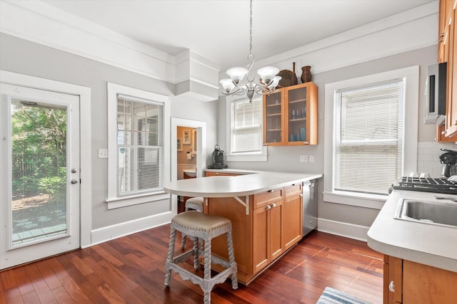 54 Grove Ave, Saint Augustine, FL 32084 - kitchen with a peninsula, a chandelier, dark wood-style flooring, glass insert cabinets, and a breakfast bar area