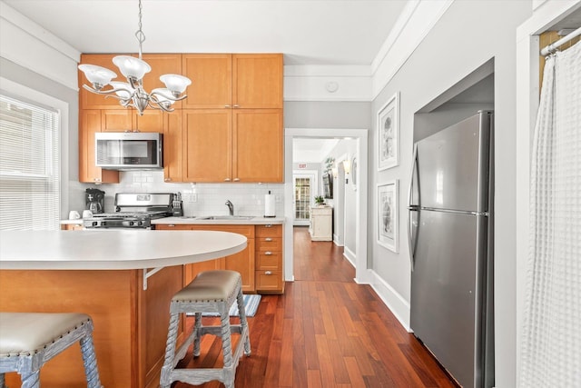 54 Grove Ave, Saint Augustine, FL 32084 - kitchen with stainless steel appliances, a sink, a chandelier, light countertops, and dark wood finished floors