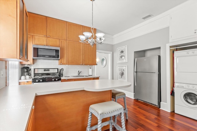54 Grove Ave, Saint Augustine, FL 32084 - kitchen with appliances with stainless steel finishes, stacked washing machine and dryer, a sink, a chandelier, and light countertops