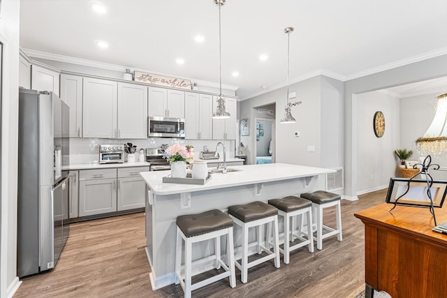 313 Aventurine Ave, Saint Augustine, FL 32086 - kitchen featuring stainless steel appliances, ornamental molding, gray cabinets, light countertops, and light wood-type flooring