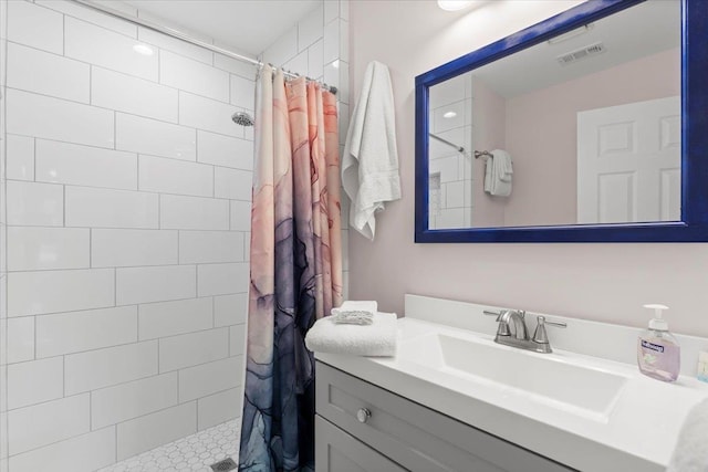 bathroom with visible vents, vanity, and a tile shower