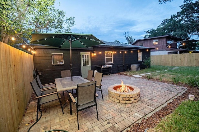 patio terrace at dusk featuring a grill, an outdoor fire pit, and central air condition unit