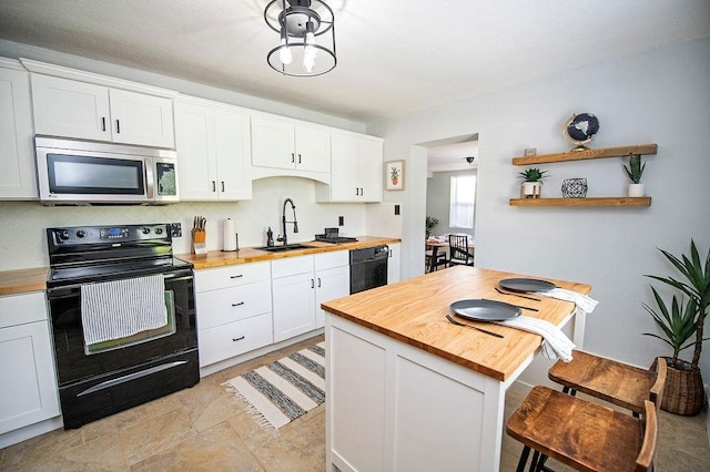 kitchen with wooden counters, a kitchen breakfast bar, white cabinetry, and black appliances