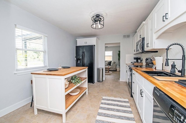 kitchen with wood counters, sink, white cabinets, and black appliances