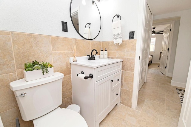 bathroom with vanity, toilet, and tile walls