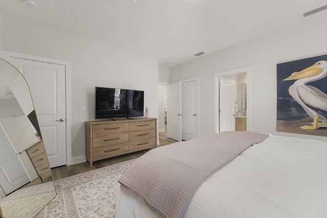 bedroom with dark hardwood / wood-style floors and connected bathroom