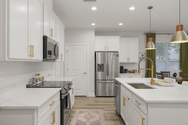 kitchen with a kitchen island with sink, white cabinets, hanging light fixtures, sink, and appliances with stainless steel finishes