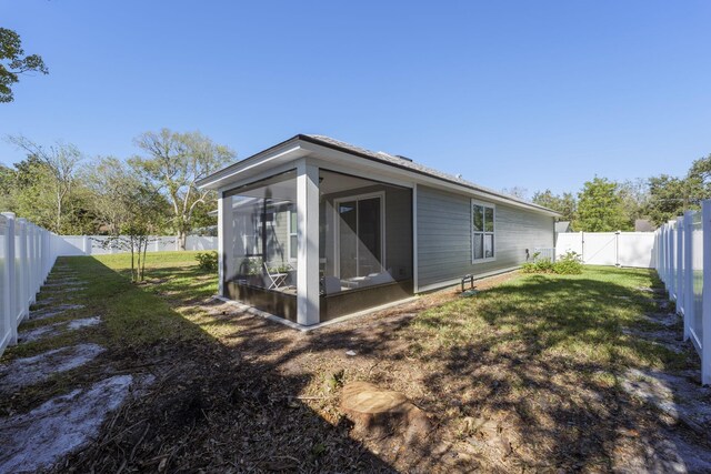 back of property with a lawn and a sunroom