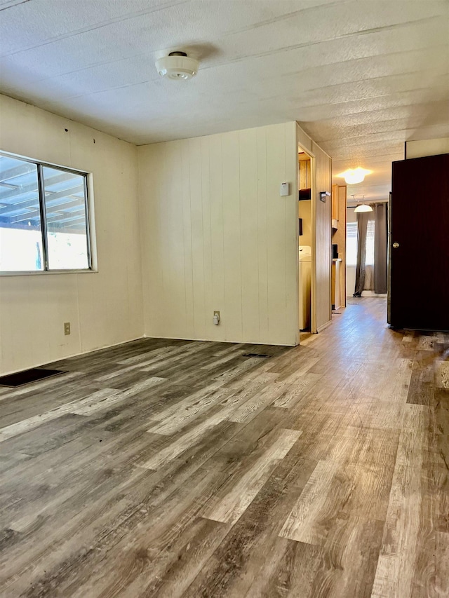 empty room with wood-type flooring, a textured ceiling, and washer / clothes dryer