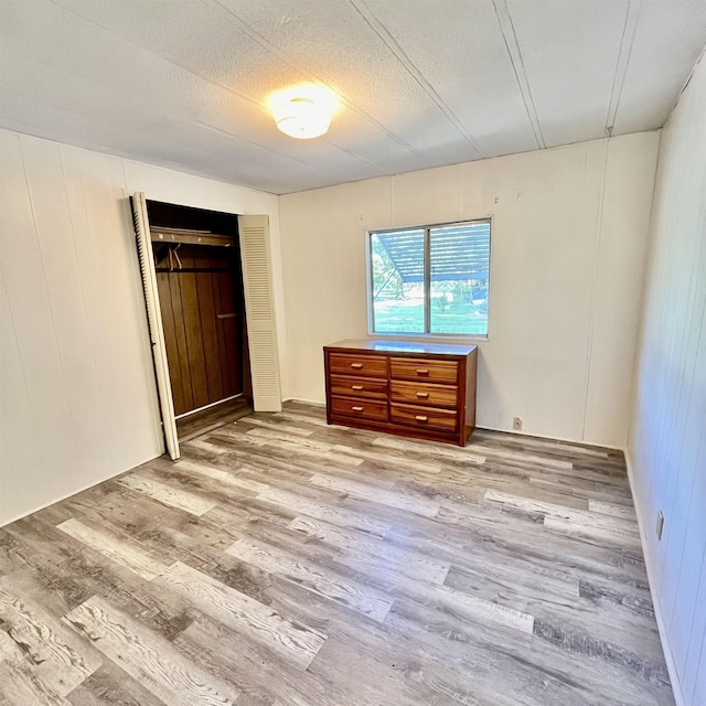 unfurnished bedroom featuring a closet, a textured ceiling, and light wood-type flooring