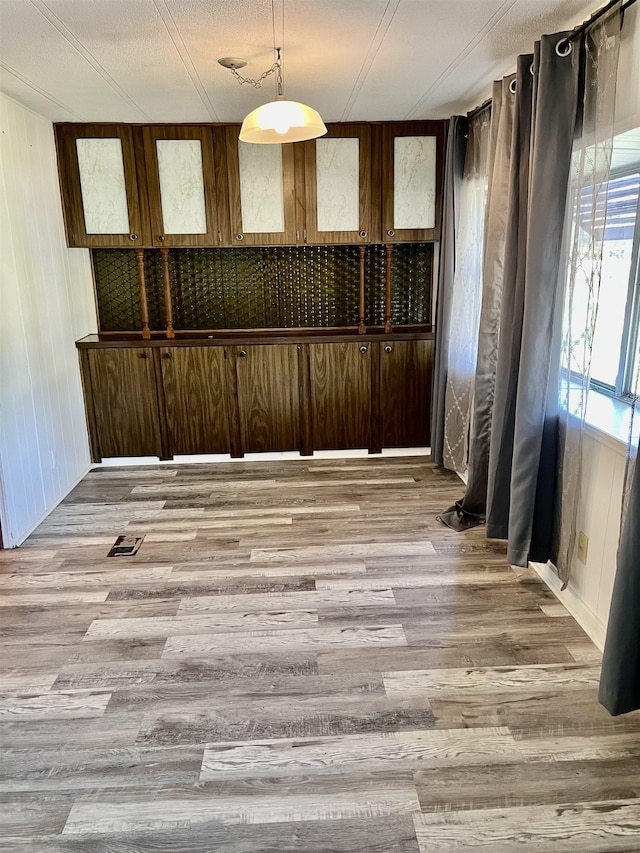 empty room with hardwood / wood-style floors, wood walls, and a textured ceiling