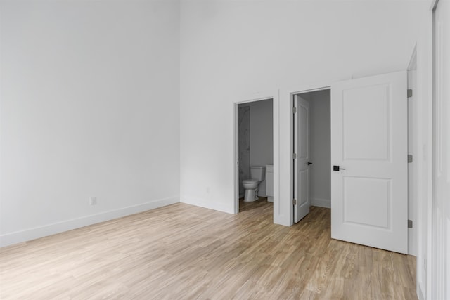 unfurnished bedroom featuring light wood-type flooring and ensuite bath