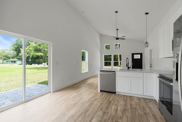 kitchen with light wood-type flooring, stainless steel appliances, sink, high vaulted ceiling, and white cabinetry