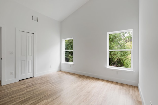 spare room featuring light wood-type flooring and high vaulted ceiling