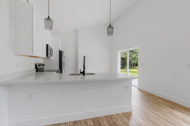 kitchen with pendant lighting, kitchen peninsula, white cabinetry, and stainless steel appliances