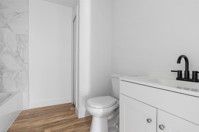 bathroom with a bath, wood-type flooring, vanity, and toilet