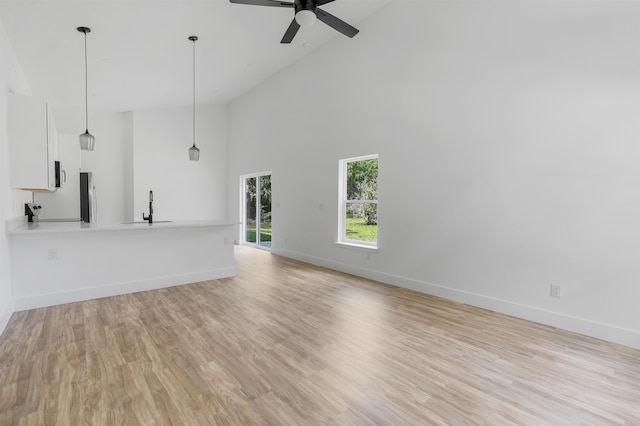 unfurnished living room with light wood-type flooring, high vaulted ceiling, ceiling fan, and sink