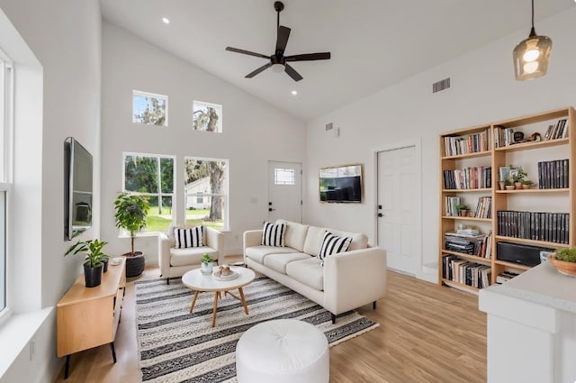 living room with ceiling fan, high vaulted ceiling, and light wood-type flooring