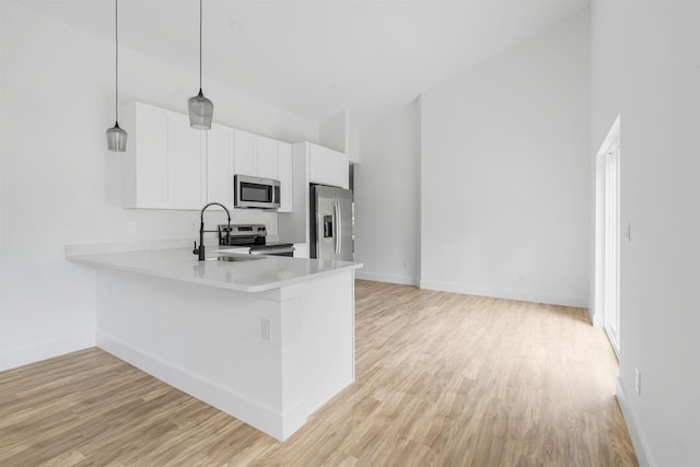 kitchen with sink, white cabinets, decorative light fixtures, and appliances with stainless steel finishes