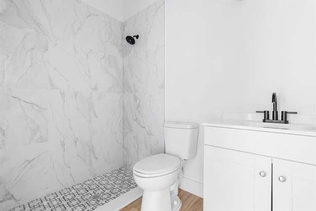 bathroom featuring toilet, hardwood / wood-style floors, vanity, and tiled shower