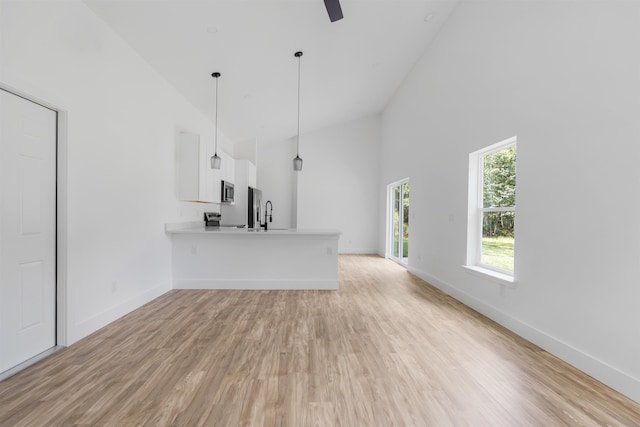 unfurnished living room with ceiling fan, light wood-type flooring, and high vaulted ceiling