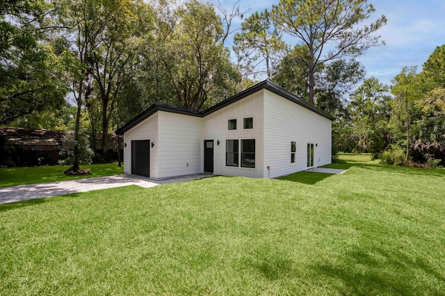 back of property featuring a garage and a yard