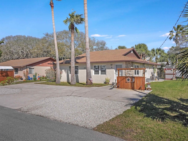 view of front of home featuring driveway, a front lawn, fence, and stucco siding