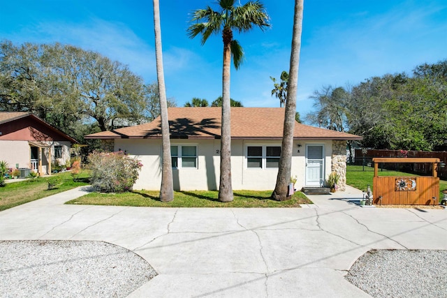 view of front of house featuring a front lawn, a shingled roof, fence, and stucco siding