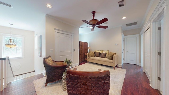 living area featuring dark hardwood / wood-style flooring, ceiling fan, and crown molding