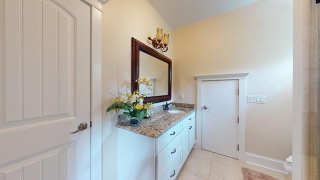 bathroom with tile patterned flooring, vanity, vaulted ceiling, and toilet