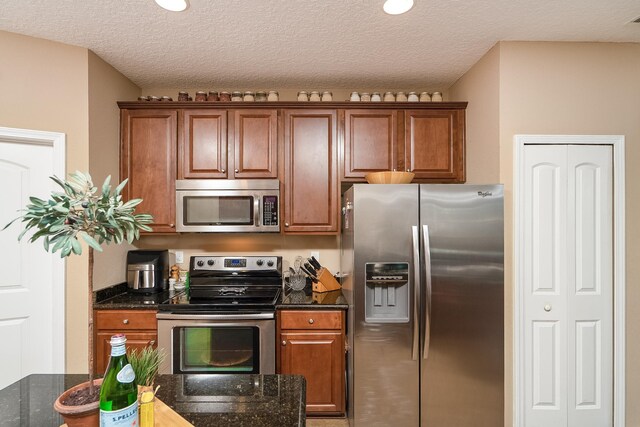 kitchen featuring a textured ceiling, dark stone countertops, and stainless steel appliances