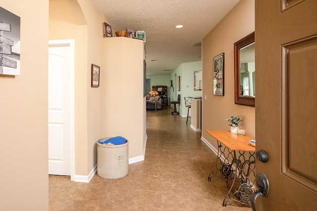 corridor with light tile patterned floors and a textured ceiling