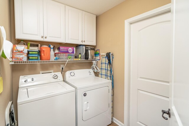 laundry room featuring washer and clothes dryer, cabinets, and a textured ceiling