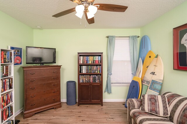 living area featuring ceiling fan, a textured ceiling, and light hardwood / wood-style flooring