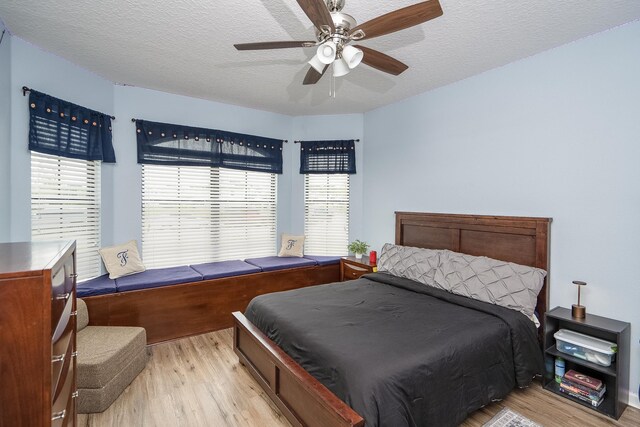 bedroom featuring ceiling fan, light hardwood / wood-style floors, and a textured ceiling