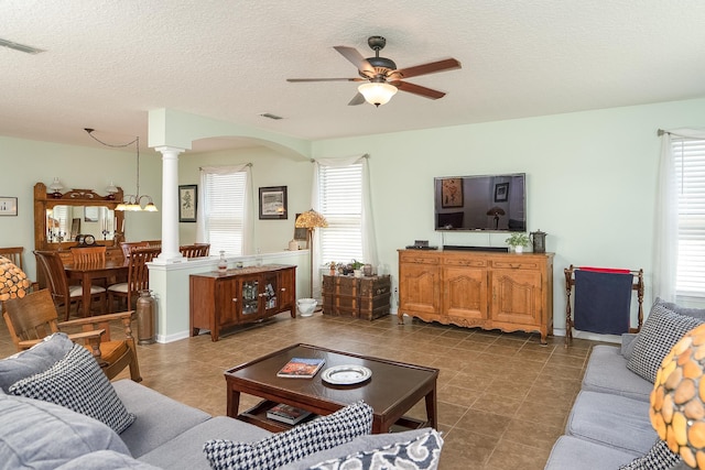 tiled living room featuring decorative columns, ceiling fan, and a textured ceiling