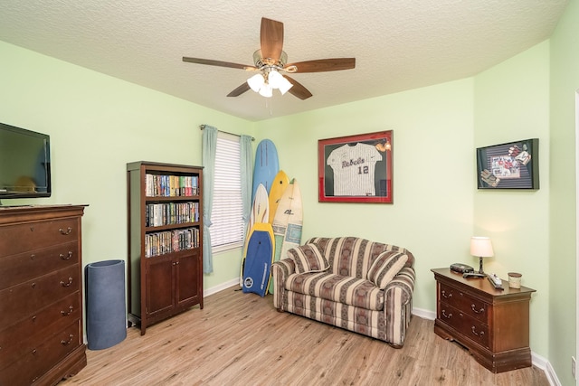 living area featuring a textured ceiling, light hardwood / wood-style floors, and ceiling fan