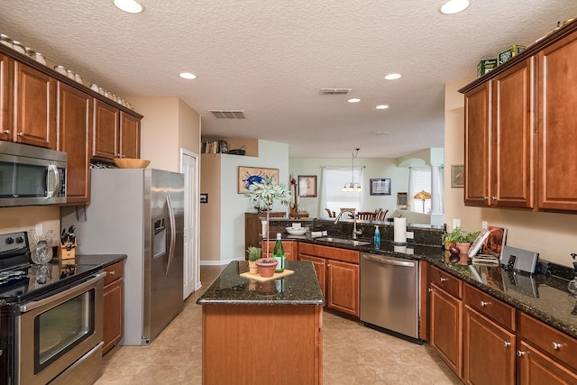 kitchen featuring kitchen peninsula, a textured ceiling, stainless steel appliances, sink, and a center island