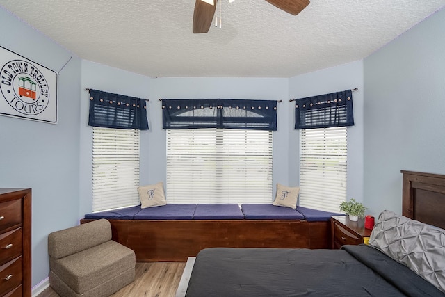 bedroom with ceiling fan, light hardwood / wood-style flooring, and a textured ceiling