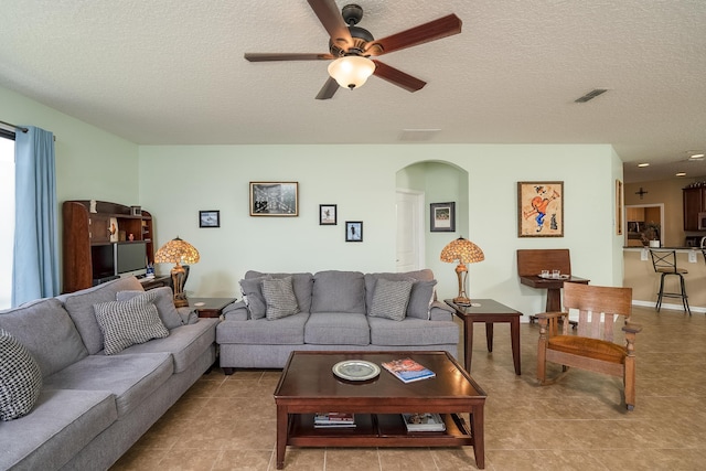 living room featuring ceiling fan, light tile patterned floors, and a textured ceiling