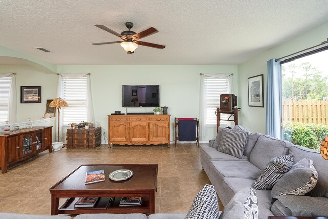 living room with ceiling fan, light tile patterned floors, and a textured ceiling