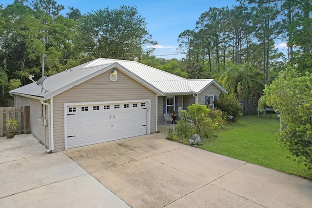ranch-style house featuring metal roof, driveway, and an attached garage